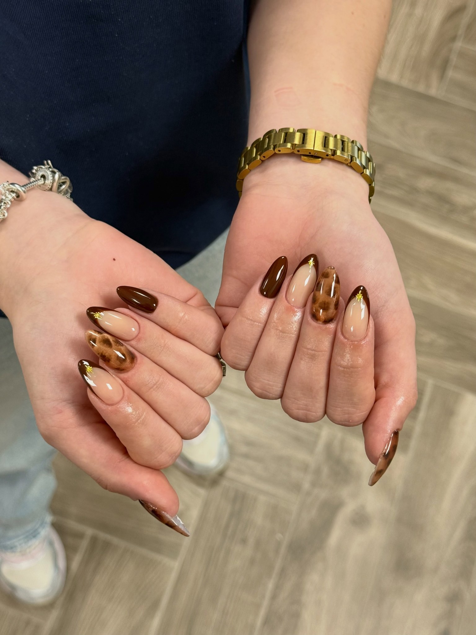 Twee handen met bruine tortoise en chrome amandelnagels